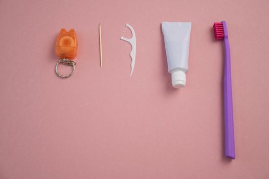 Oral hygiene products on a pink background. Toothbrush toothpaste dental floss and toothpick. Copy space