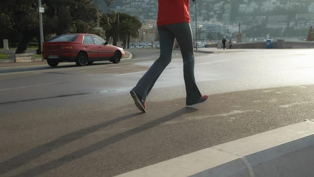 woman legs running on the street wearing in trousers and sneakers.