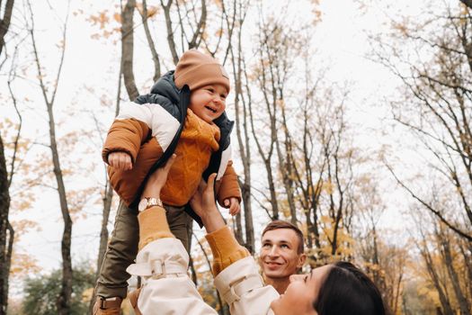 Father and mother with son walking in the autumn Park. A family walks in the Golden autumn in a nature Park