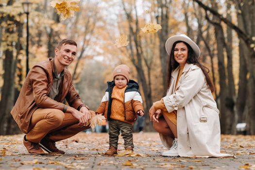 Father and mother with son walking in the autumn Park. A family walks in the Golden autumn in a nature Park