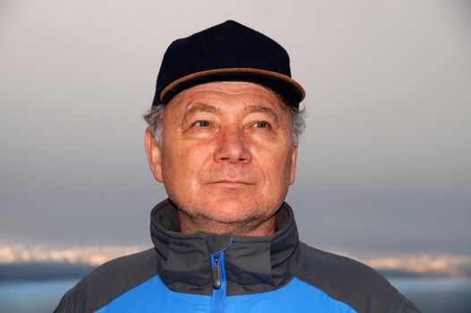 portrait of a smiling middle aged man in a cap on a natural background