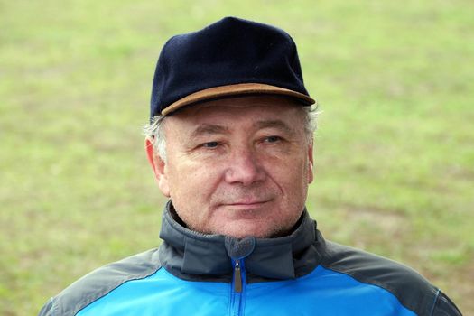 portrait of a smiling middle aged man in a cap on a natural background