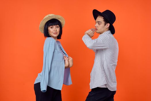 man and woman in hats posing fashion orange background. High quality photo
