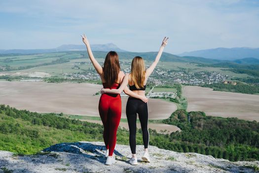 Two girls play sports on a cliff. Yoga in nature. A healthy lifestyle. It's a good habit.
