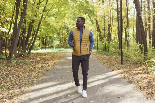 African american student walking in the park in autumn season.