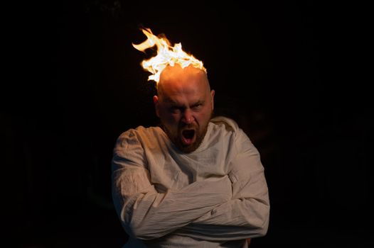 Bald man in a straitjacket with a burning head on a dark background