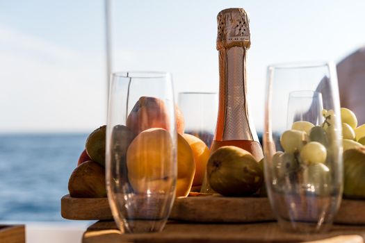 Fruit tray and bottle of champagne for romantic date on a yacht, close up