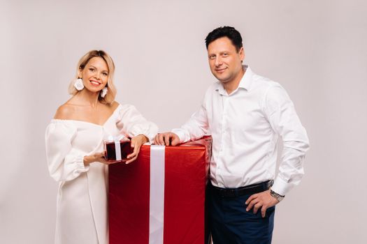 Portrait of a man and a woman with a large gift on a beige background.