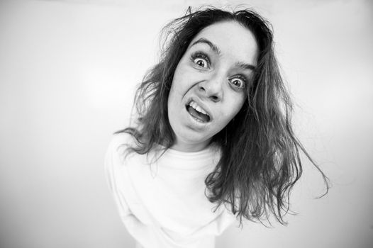 Close-up portrait of insane woman in straitjacket on white background. Monochrome