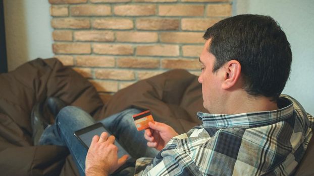 The man using digital tablet for pay online. Holding in the hands credit card