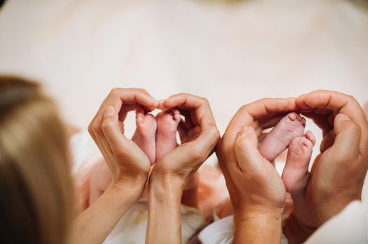 the newborn's legs are held in the hands of the mother and father in the form of a heart. children's feet in the hands of parents.