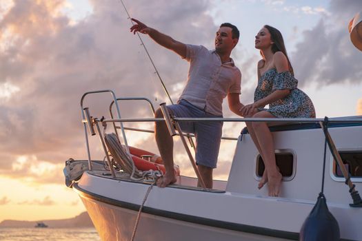 Beautiful loving couple looking at sunset from the yacht