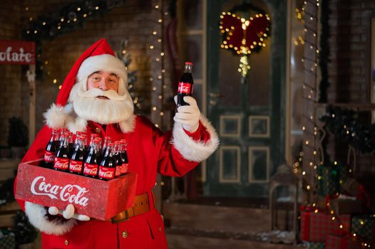 06.11.2020 Russia, Novosibirsk: Portrait of Santa Claus holding a package of Coca Cola bottles. Christmas greeting card.
