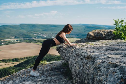 Beautiful girl is engaged in sports in the mountains. Sports on self-isolation.