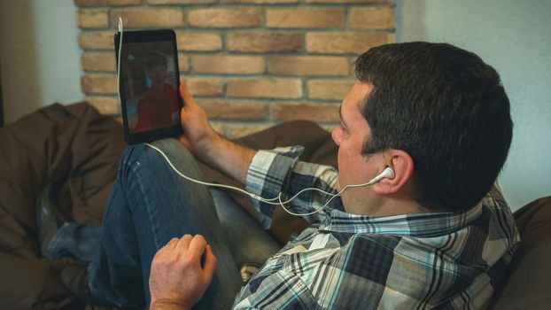 Man speaking by tablet video chat with friend