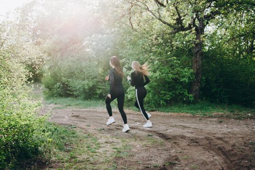 Two girls jogging in the woods. Running with distance.