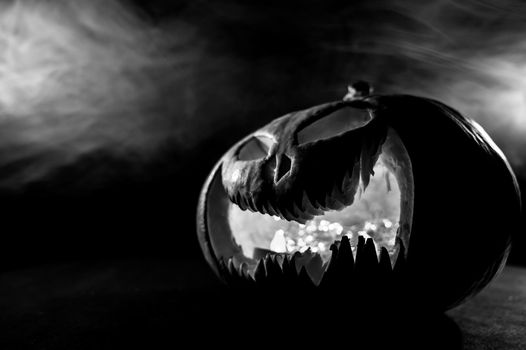 A creepy pumpkin with a carved grimace in the smoke. Jack o lantern in the dark