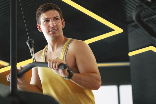 Young bodybuilder doing heavy weight exercise for biceps in a gym, close up