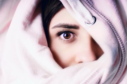 The woman hides her face behind the hood. Stylish female posing in a hoodie. Portrait of a young woman covering her face with a hood.
