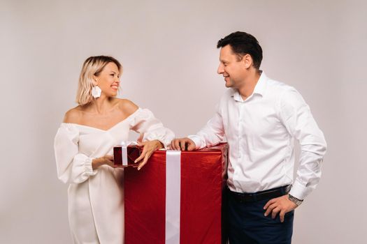 Portrait of a man and a woman with a large gift on a beige background.