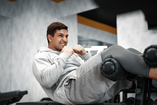 Young athlete doing abs exercises workout in modern gym, close up