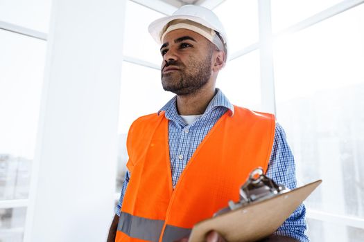 Foreman at work on construction site checking his notes on clipboard, close up