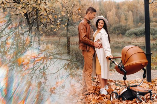 Father and mother on a walk with a stroller in the autumn Park. The family walks through the nature Park in the Golden autumn