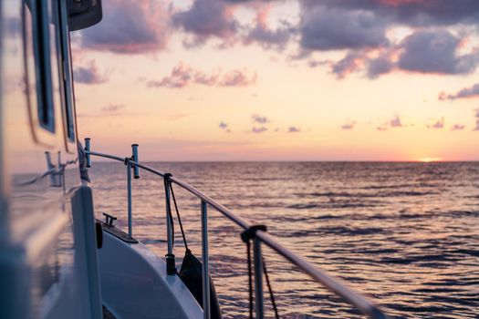 Deck of white yacht sailing in open sea at sunset, close up