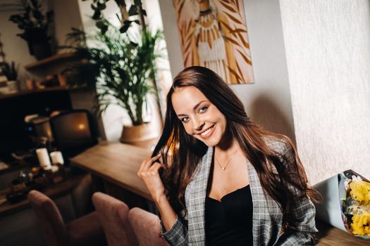 Portrait of a young European girl with long hair in a coffee shop in the evening light, a tall Girl in a jacket with long hair in a cafe.