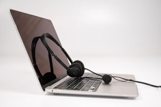 Headset on laptop keyboard on white background