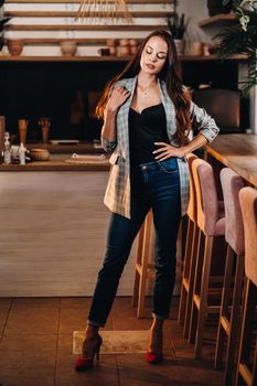 Portrait of a young European girl with long hair in a coffee shop in the evening light, a tall Girl in a jacket with long hair in a cafe.