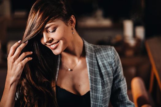 Portrait of a young European girl with long hair in a coffee shop in the evening light, a tall Girl in a jacket with long hair in a cafe.