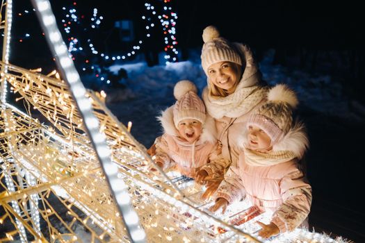 Mom and kids in the evening city with night Christmas lights.