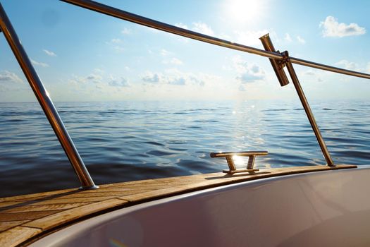 Deck of white yacht sailing in open sea at sunset, close up
