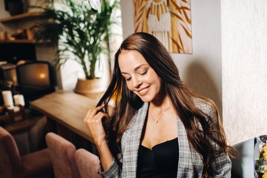 Portrait of a young European girl with long hair in a coffee shop in the evening light, a tall Girl in a jacket with long hair in a cafe.