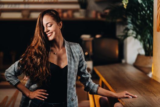 Portrait of a young European girl with long hair in a coffee shop in the evening light, a tall Girl in a jacket with long hair in a cafe.