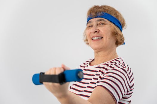 Happy old woman doing fitness exercises with dumbbells on a white background. Elderly lady doing fitness to maintain health