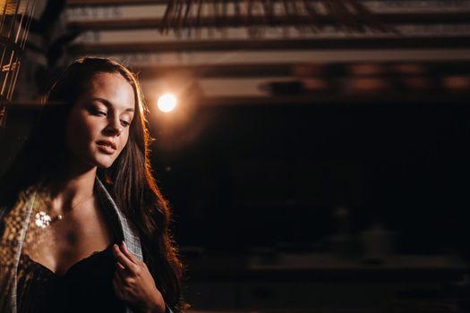 Portrait of a young European girl with long hair in a coffee shop in the evening light, a tall Girl in a jacket with long hair in a cafe.