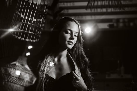 Portrait of a young European girl with long hair in a coffee shop in the evening light, a tall Girl in a jacket with long hair in a cafe. black and white photo.