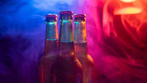 Three bottles of beer in a blue-pink mist