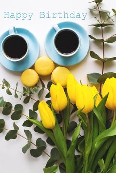 two blue cup of coffee with yellow tulips on an old table, the inscription happy birthday