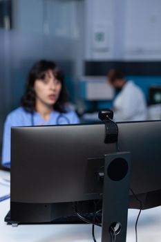 Close up of webcam on modern computer for video call and remote communication in office. Nurse using camera on monitor for video conference and online telemedicine, working late at night.