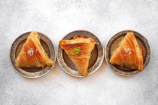 Turkish baklava on oriental metal plate on white table, close up