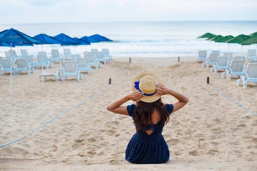 Beautiful girl in a hat sits on a beach.