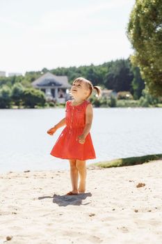little beautiful girl on the river bank smiles and looks up