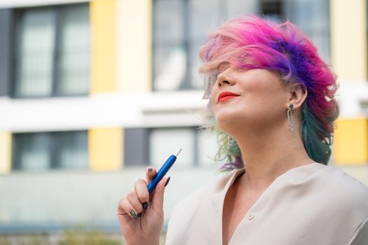 Caucasian woman with colored hair smokes an electronic cigarette