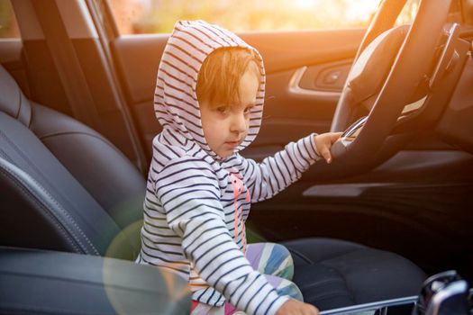 cute toddler plays driver in parents modern car. adorable child explore drivers sear of premium car. baby driver, young driver holds steering wheel in the car