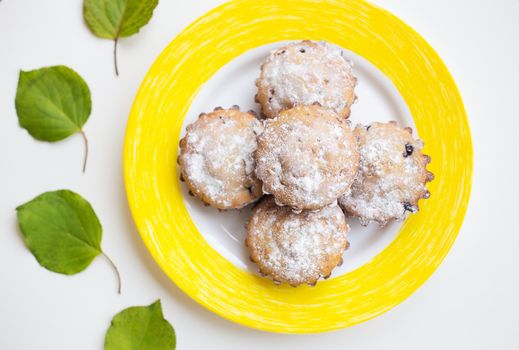 Beautiful cakes with powdered sugar on a yellow plate