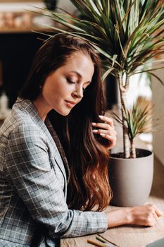 Portrait of a young European girl with long hair in a coffee shop in the evening light, a tall Girl in a jacket with long hair in a cafe.