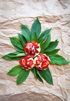 Beautiful and bright cupcakes with strawberries lie on green leaves.